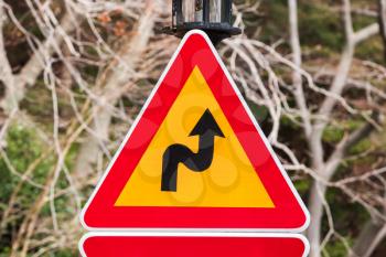 Dangerous turns, triangle warning traffic sign near rural road