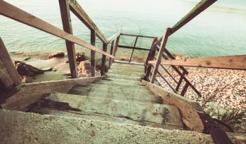 Perspective view of old wooden stairs down to beach. Zakynthos island, Greece. Vintage toned photo