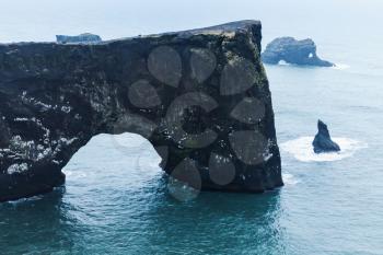 Natural stone arch. Scenic landscape of Dyrholaey Nature Reserve, south coast of Iceland, Europe. Blue toned photo background