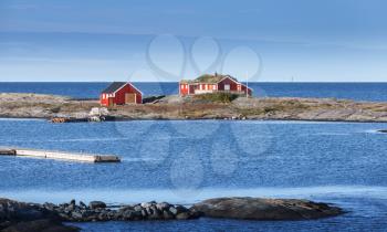 Rural Norwegian landscape, traditional red wooden houses on rocky island. Norway, Trondheim district