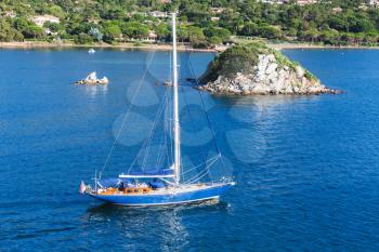 Porto-Vecchio bay, Corsica island, France. White sailing yacht go near small rocky island