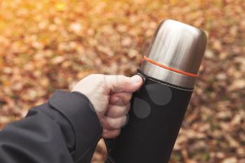 Stainless steel tourist thermos in male hand