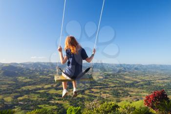 Red haired teenage girl swinging on a swing. Montana Redonda. Dominican Republic