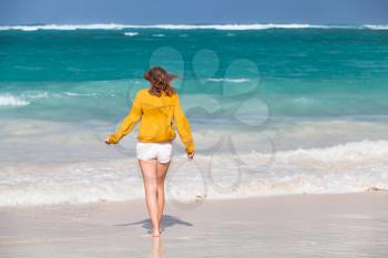 Teenage girl walking on the beach. Atlantic ocean coast, Dominican Republic