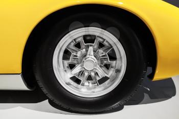 Yellow luxury Italian vintage sport car wheel on chromed disc, close up photo with selective focus