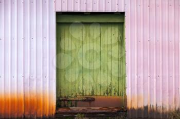 Closed green wooden door in industrial metal wall, background texture
