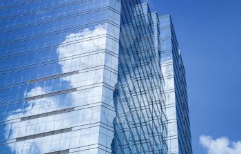 Abstract modern architecture background, office tower made of blue glass and steel with reflections of cloudy sky