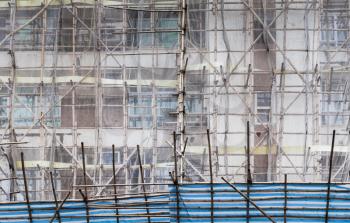 Block of flats is under renovation, facade fragment with bamboo scaffolding structures, Hong Kong