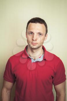 Studio portrait of young adult European man in red polo shirt