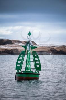 Green buoy with cone topmark. Navigation equipment of Reykjavik bay, Iceland