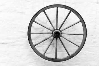 Old wooden cart wheel hanging on rural wall, black and white