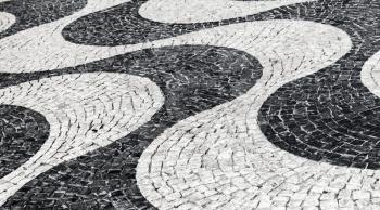 Typical portuguese cobblestone pavement pattern of black and white waves. Lisbon, Portugal