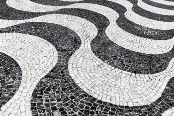 Typical portuguese cobblestone handmade pavement pattern of black and white waves. Lisbon, Portugal