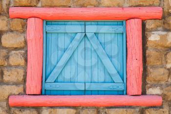 Window with blue closed shutters and red frame in old stone wall, background photo texture
