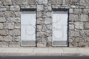 Two gray metal doors in gray stone wall. Background photo texture