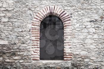 Arched window in old gray stone wall. Background photo texture