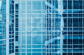 Modern architecture abstract fragment, walls made of glass and steel with reflections of blue sky