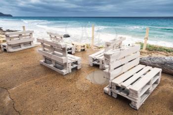 Standard white wooden furniture made of cargo pallets, cheap seaside bar terrace. Porto Santo island, Madeira archipelago, Portugal