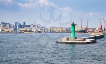 Entrance to the Port of Naples, coastal cityscape with green lighthouse tower on concrete pier