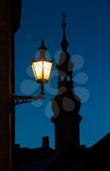 Old street lamp and church silhouette at night. Old town of Tallinn, Estonia