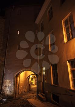 Dark street with illuminated gateway at night in old town of Tallinn, Estonia