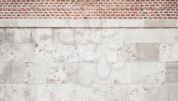 Wall made of gray stone blocks and red bricks, frontal background photo texture