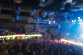 Blurred photo background, music concert hall with colorful illumination and crowd of people