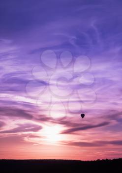 Hot air balloon flies in colorful evening sky, vertical background photo