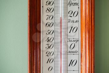 Close-up photo of old alcohol thermometer showing indoor temperature. Text labels in Russian means warm, freezing of water