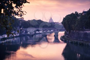 Rome cityscape with old bridge over Tiber river in evening