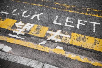 Look left. Caution road marking for pedestrians shows direction of approaching traffic in Hong Kong city