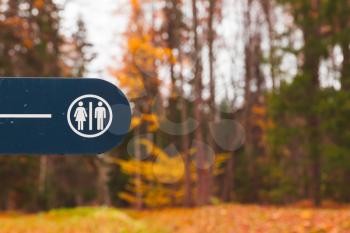 Restroom sign on blue board in autumn park