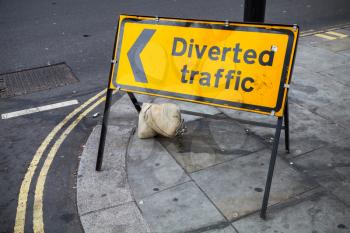 Diverted traffic. Yellow road sign stands on street of London city