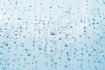 Water drops are on light blue glass, background texture