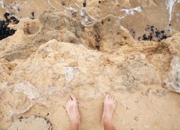 Male bare feet stand on coastal sandstone rock. Travel lifestyle background