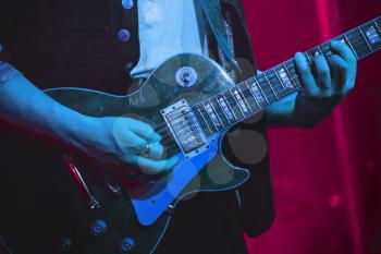 Guitarist plays electric guitar on a stage, photo with soft selective focus