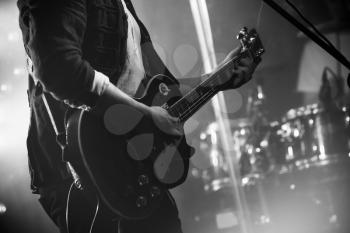 Rock and roll music black and white background, electric guitar player on a stage, photo with soft selective focus