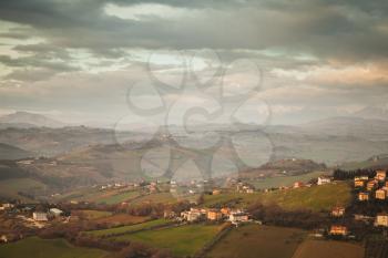 Italian countryside, rural landscape. Province of Fermo, Italy. Villages and fields on hills under cloudy sky. Vintage toned photo