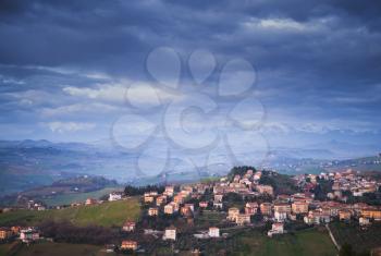 Italian countryside. Rural landscape. Province of Fermo, Italy. Village on hills under dark cloudy sky