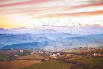 Colorful morning panorama of Italian countryside. Province of Fermo, Italy. Villages and on hills under cloudy sky