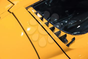 Luxury yellow vintage roadster fragment, aerodynamics air intake grille, Italian car design