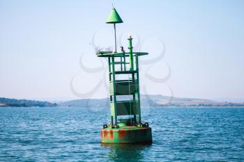 Green navigation buoy with cone topmark floats on sea water. Bay of Burgas, Black Sea, Bulgaria