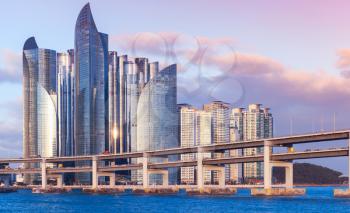 Busan, South Korea. Cityscape of Haeundae District with luxury skyscrapers and bridge in evening light