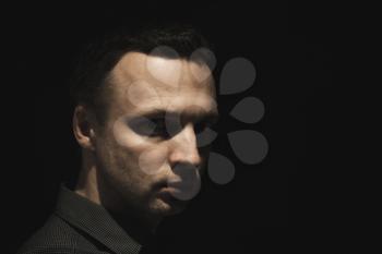 Portrait of young European man over black background, low key studio photo