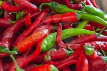 Red and green hot peppers lay on a marketplace counter
