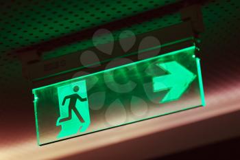 Illuminated green emergency exit sign, indicating that the emergency escape route is to the right