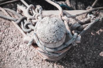 Old mooring bollard with ropes stands on concrete pier in harbor, top view