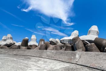 Breakwater with empty road and concrete blocks under cloudy sky. Industrial background photo