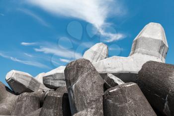 Gray breakwater blocks made of concrete are under cloudy sky. Industrial background photo
