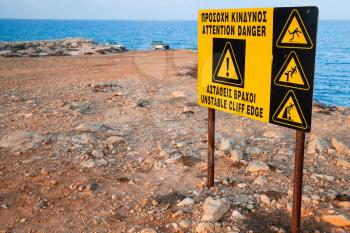 Attention, danger, unstable cliff edge. Warning sign on the coast of Cyprus island
